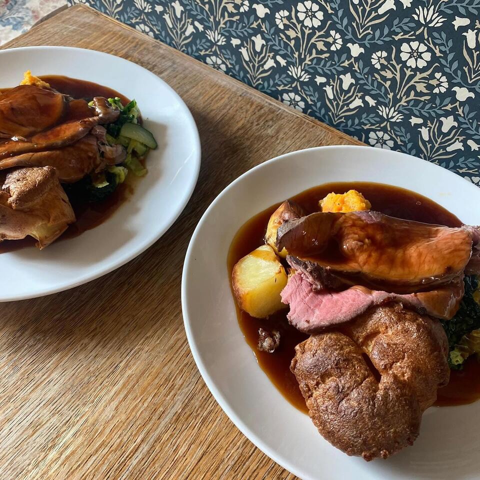 Two plates of Sunday roast beef with Yorkshire puddings and gravy