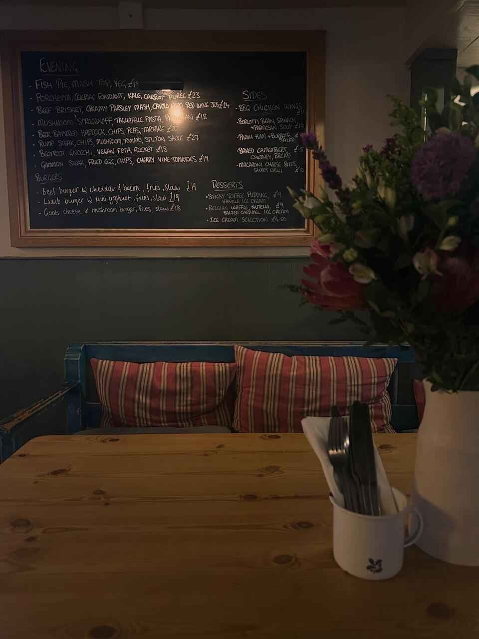 The chalkboard menu above a blue bench with striped cushions